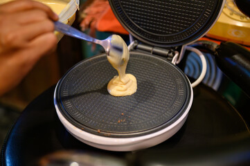 Homemade waffle pastry maker making and pouring batter dough on steel pan - obrazy, fototapety, plakaty