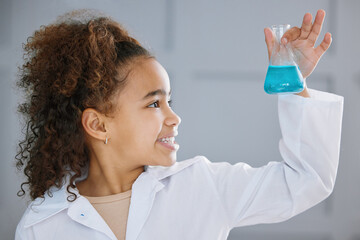 Observing the reaction. an adorable little girl wearing a labcoat while holding a beaker full of blue liquid.