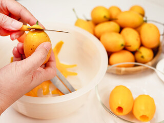 man peel ripe juicy peeled marian plum or plum mango over white kitchen background, thailand fresh...
