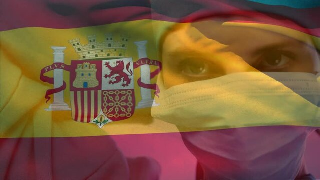 Animation of waving spanish flag against caucasian female surgeon wearing surgical mask at hospital