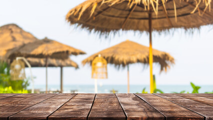 Empty wood table top and blurred seaside restaurant in tropical resort in summer banner background...