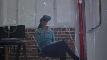 Animation of connections with icons over caucasian businesswoman wearing vr headset in office - Powered by Adobe