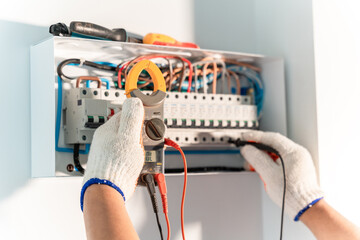Hand of Electrician engineer tests electrical installations and wires on relay protection system....