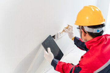 Asian electrician tester measuring voltage at the power socket.