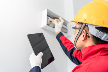 Asian electrician or engineer tester measuring voltage at fuse switch box in the house. Bay control...