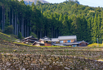 Traditional Japanese farm house over stone walls and terraced fields in mountain village