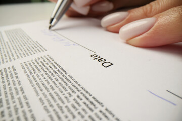 Woman writes date above line after signing contract papers