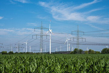 Pylons, power lines and wind turbines with a cornfield in Germany - 596165369