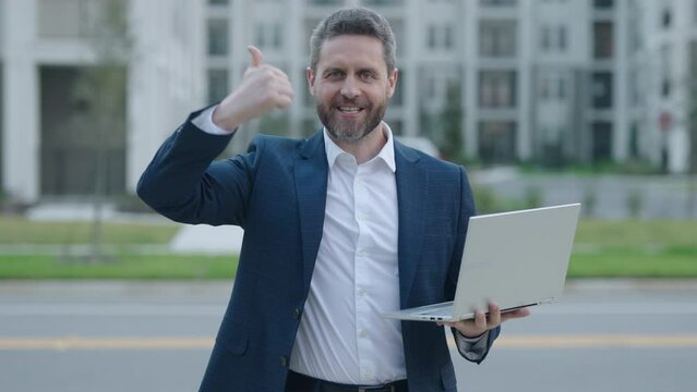 Serious business man working on laptop. Handsome business man wearing formal suit. View of a attractive business man outdoor. Handsome middle age man walking to the business meeting.