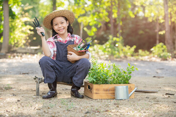 Cute little child girl with seedlings. volunteering, charity, people and ecology concept - volunteers hands planting tree seedling in park. Asian little girl holding a seedling.