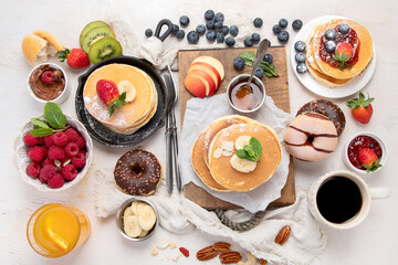 Pancakes with fresh fruits, donuts and coffee on a white background.