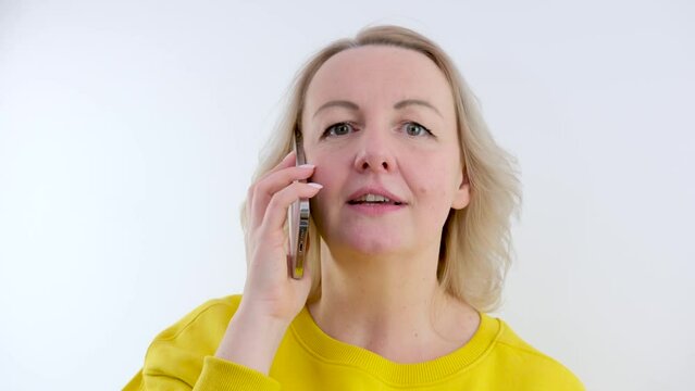 woman talks a lot on the phone fast conversation talkative blonde girl talking with social taxi services on a white background bright orange yellow clothes or face closeup