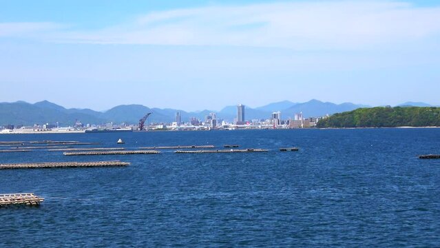 瀬戸内海に浮かぶ牡蠣養殖筏と広島市沿岸の風景を船から移動撮影  4K  2023年4月23日