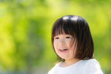 新緑の初夏の公園で遊ぶ笑顔の女の子