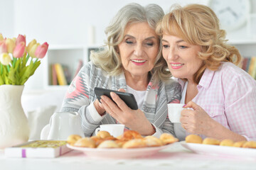 two senior women using smartphone at home