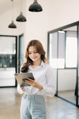 Confident business expert attractive smiling young woman holding digital tablet  on desk in creative office..