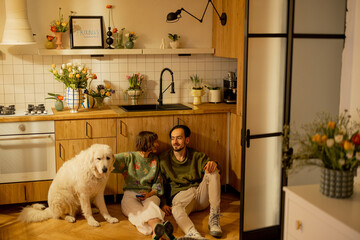 Young couple sit relaxed together with a cute dog on kitchen at home. Home coziness and domestic lifestyle concept