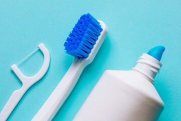 White toothbrush with toothpaste and dental floss on a green background