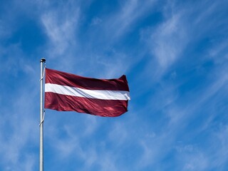 The national flag of Latvia against the sky.