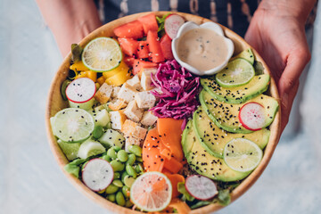 Healthy vegetarian salad. Buddha bowl in woman hands. Top view.