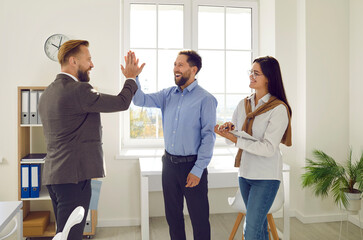 Businessman giving high five to colleague at meeting. Business people celebrating achievement, teamwork results, success of teamwork. Cheerful employees working in office