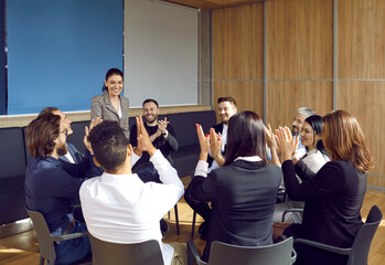 Team leader's work being greatly appreciated at office meeting. Group of happy smiling people applauding to show respect and recognition to woman who has achieved good results in her job