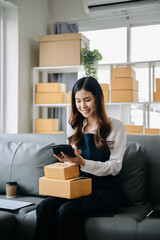 .Young business owner woman prepare parcel box and standing check online orders for deliver to customer on tablet, laptop Shopping Online concept.