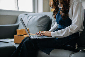  Woman hand using a laptop, smartphone and tablet and writing notebook at the office of her business online shopping. In home .