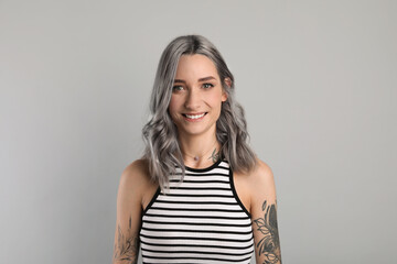 Obraz premium Portrait of smiling woman with ash hair color on light grey background