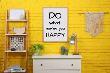 Affirmation. Poster with phrase Do What Makes You Happy on yellow brick wall in room