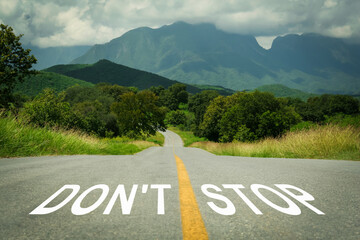 Motivational phrase. Words Don't Stop written on empty road leading to mountains