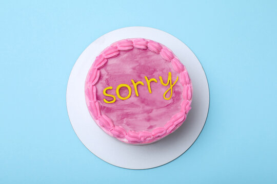 Apology. Cake with word Sorry of cream on light blue background, top view
