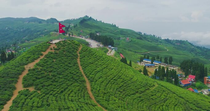 Drone flies close to Nepal's flag fluttering proudly amidst the lush green tea gardens of Kanyam, Ilam. A touristic destination, this shot captures the beauty of Nepal's natural landscape and beauty.