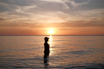 woman standing in the sea during the sunset