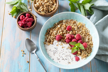 Diet nutrition concept. Healthy breakfast cereal bowl homemade granola with fresh raspberry and chia seeds on a rustic table.