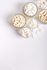 Organic food supplements, vitamins and minerals in glass jars from above on white background. 