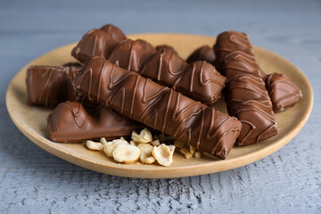 Sweet tasty chocolate bars with nuts on grey wooden table, closeup