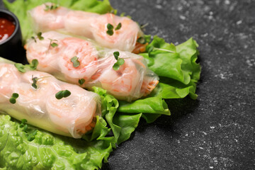 Tasty spring rolls served with lettuce and microgreens on grey textured table, closeup