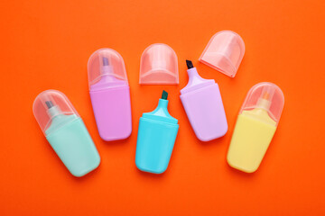 Many colorful markers on orange background, flat lay