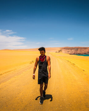 man walking in the desert yellow beaches paracas peru