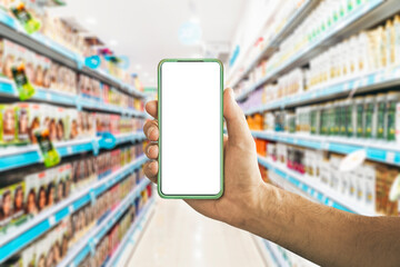Smartphone and shopping. Hand with a blank smartphone screen on the background of the supermarket counters. App, shopping, grocery concept.