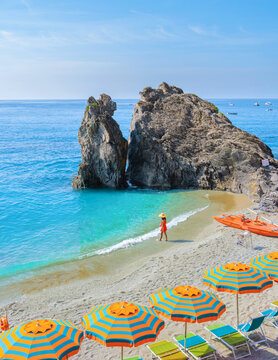 Asian women visit a Pebble beach of Monterosso Cinque Terre Italy, Chairs and umbrellas on the beach