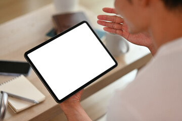Cropped image of man using digital tablet in living room. White empty screen for montage your graphic display