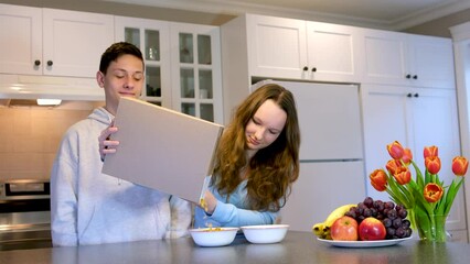 teenagers boys and girl cooking Breakfast poured from a box of cereal on the box can Your advertising empty space for text space delicious food spend time together fun brother and sister