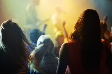 Music concert, crowd and people singing at night performance for gen z festival with party lights, dancing and cheers. Rock band on stage at event and crowd dance, audience rear or women fans