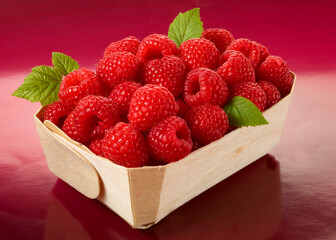 Himbeeren im Korb vor rotem Fond