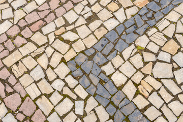 Fototapeta premium A road paved with stones, a green grass between stones on the sidewalk.