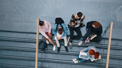 Studying as a group before exams, college students sit on campus and have a discussion on their school work