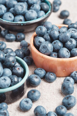 Three ceramic bowls with blueberries and berries scattered around.