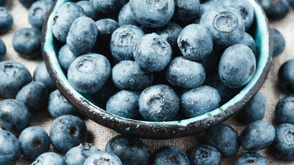 Blueberries with water drops in a ceramic bowl and scattered around.